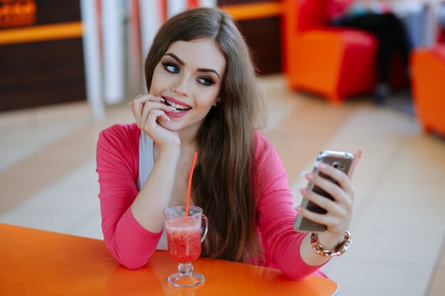 Young girl biting her finger while looking at her smartphone