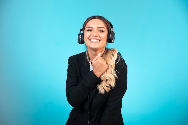 Young girl in black blazer wearing headphones and having fun.