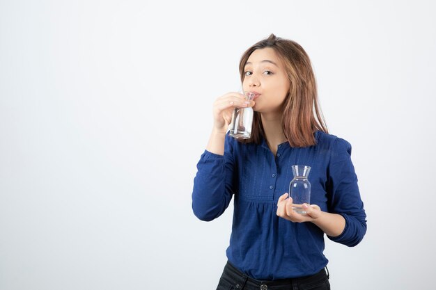 Молодая девушка в синей блузке, выпивая стакан воды.