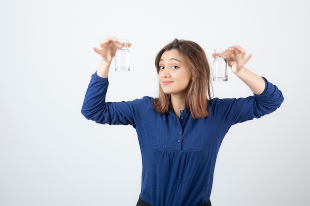 молодая девушка в голубой блузке, показывая стакан воды.