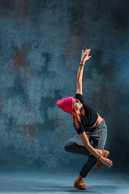 Young girl break dancing on wall background.