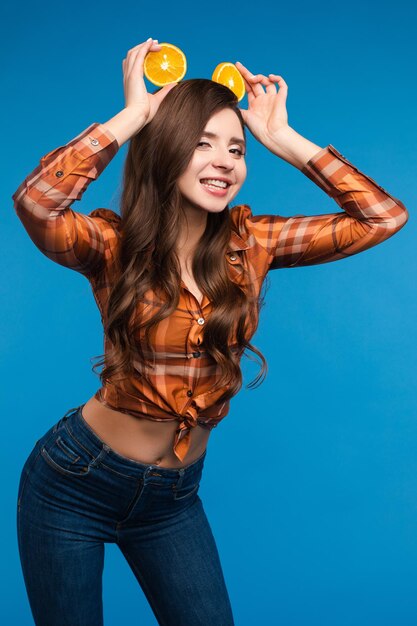 Young girl in casual clothes hiding her face behind fruits