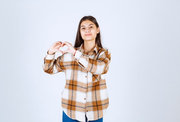 Young girl in casual clothes standing and posing on white wall. 