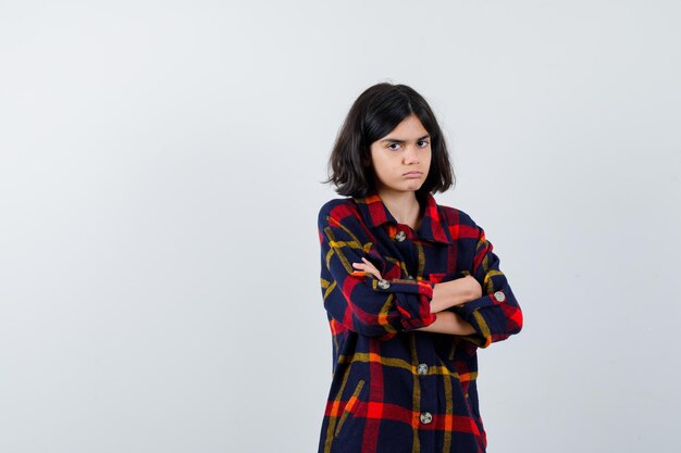 Young girl in checked shirt standing arms crossed and looking cute , front view.