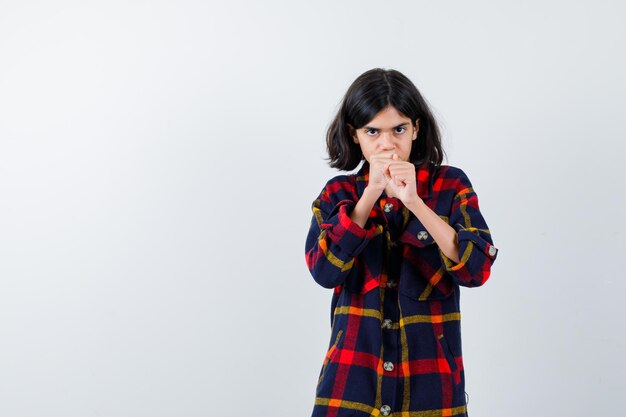 Young girl in checked shirt standing in boxer pose and looking powerful , front view.