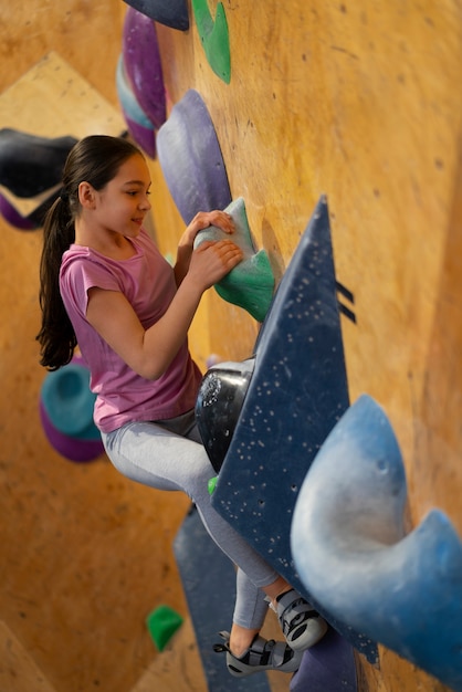 Foto gratuita giovane ragazza che si arrampica al chiuso nell'arena