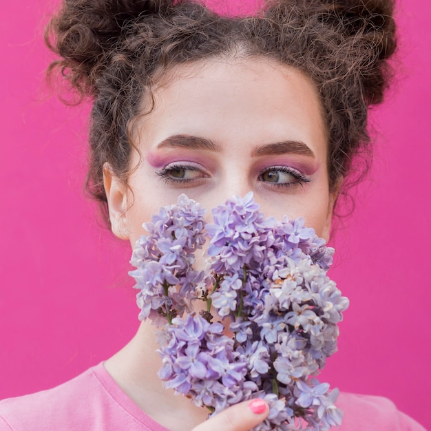 Foto gratuita ragazza che copre il viso di fiori lilla