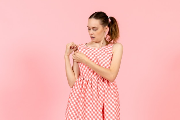 young girl in cute bright dress checking it on pink