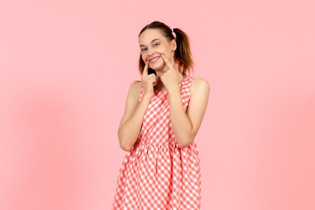 Free photo young girl in cute bright dress trying to smile on pink