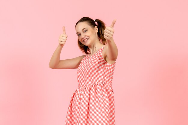 молодая девушка в милом ярком платье со счастливым выражением лица на розовом