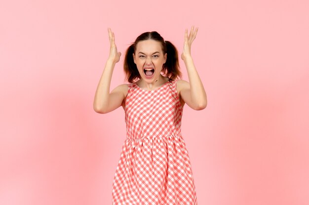 young girl in cute bright dress with rageful expression on pink