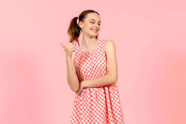 young girl in cute bright dress with smiling expression on pink