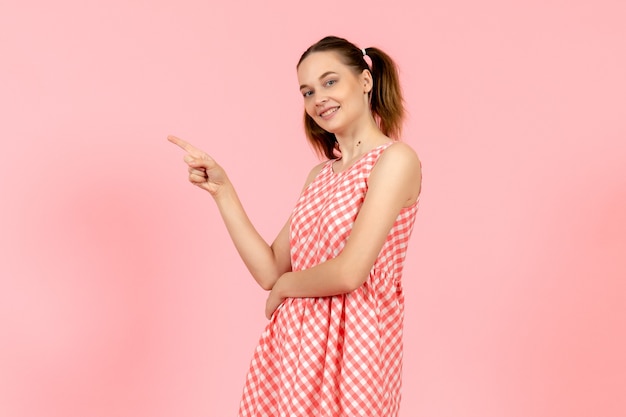 Young girl in cute bright dress with smiling expression on pink