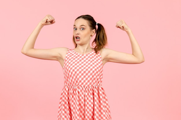 young girl in cute pink dress flexing on pink