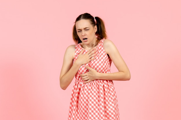 Free photo young girl in cute pink dress having breath problems on pink