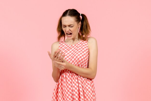 Free photo young girl in cute pink dress hurt her arm on pink