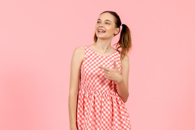 young girl in cute pink dress looking aside and smiling on pink