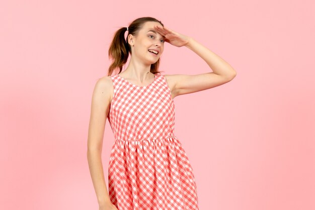 young girl in cute pink dress looking at distance on pink