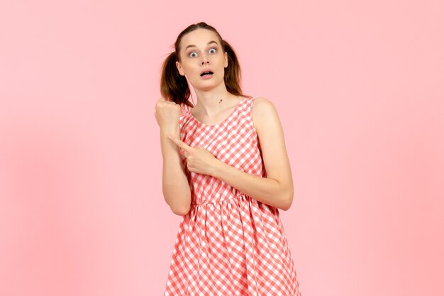 young girl in cute pink dress pointing at time on pink