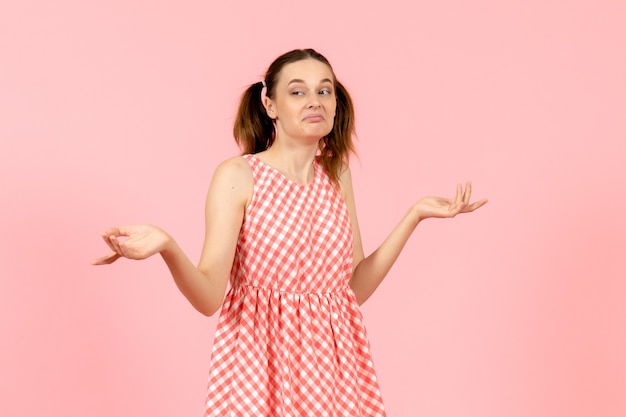 young girl in cute pink dress posing with confused face on pink