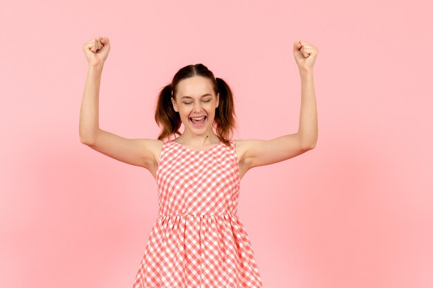 Free photo young girl in cute pink dress rejoicing on pink