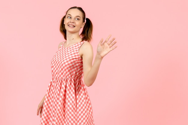 young girl in cute pink dress smiling and waving on pink