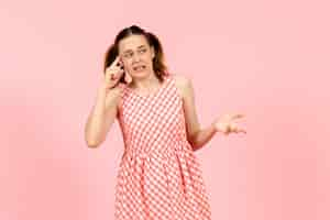 Free photo young girl in cute pink dress with confused expression on pink