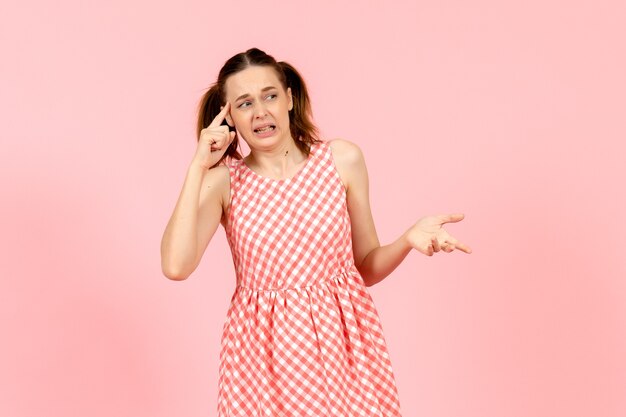 young girl in cute pink dress with confused expression on pink