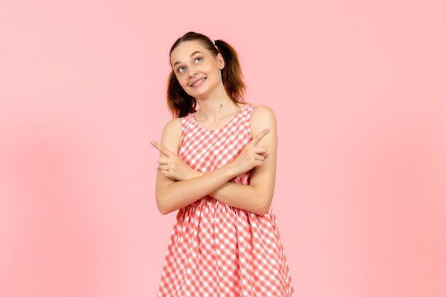 young girl in cute pink dress with dreaming expression on pink