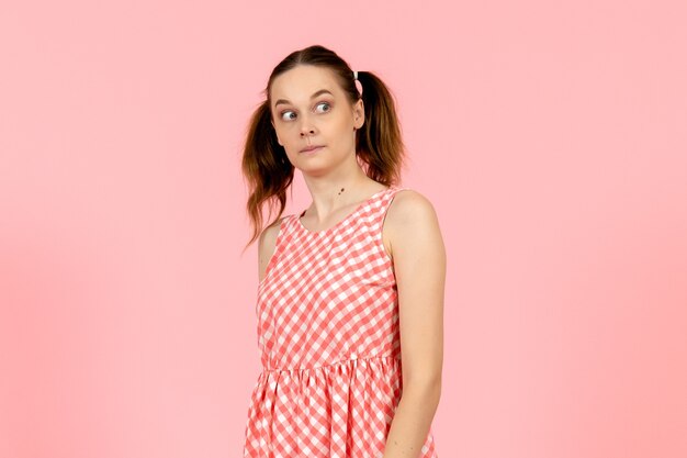 young girl in cute pink dress with funny expression on pink