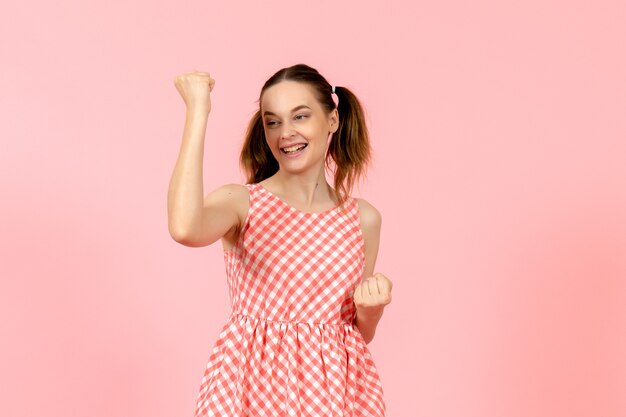 young girl in cute pink dress with rejoicing expression on pink