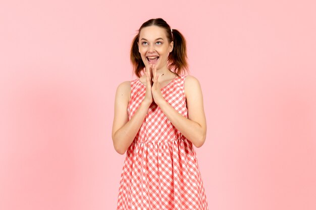 Foto gratuita giovane ragazza in abito rosa carino con espressione sorridente sul rosa