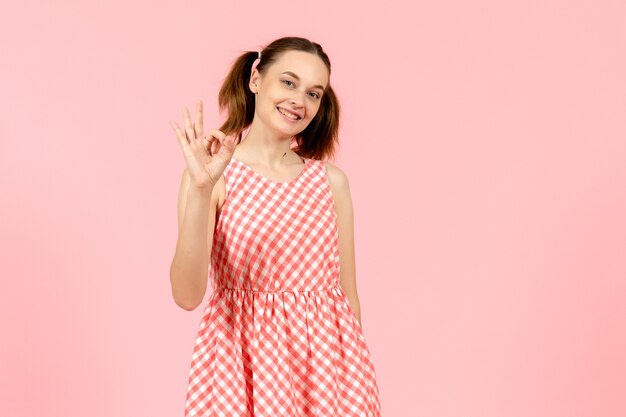 young girl in cute pink dress with smiling expression on pink