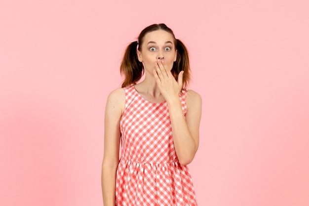 young girl in cute pink dress with surprised face on pink