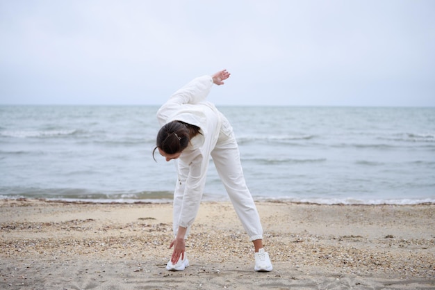 Young girl doing exercises at the beach in the morning High quality photo