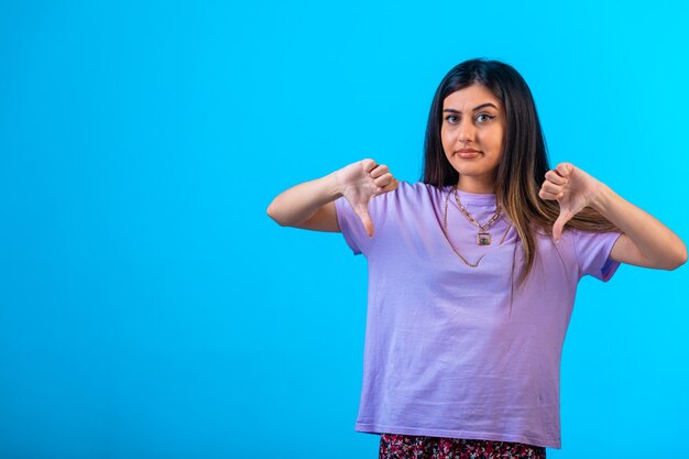 Young girl doing thumbs down sign in both hands