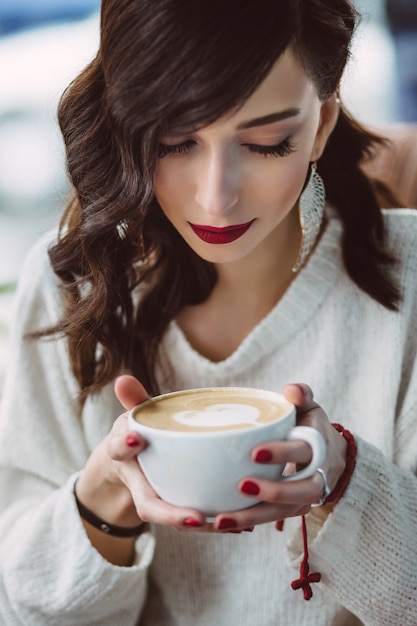 トレンディなカフェでコーヒーを飲む若い女の子