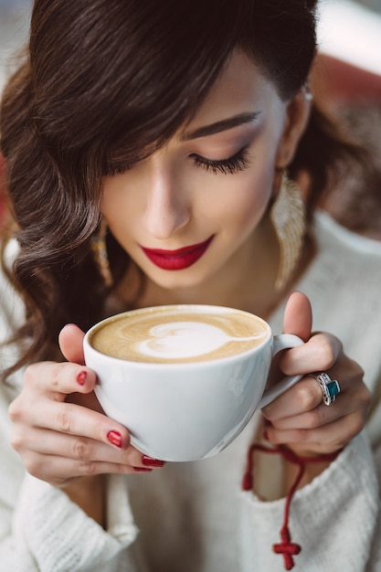 トレンディなカフェでコーヒーを飲む若い女の子