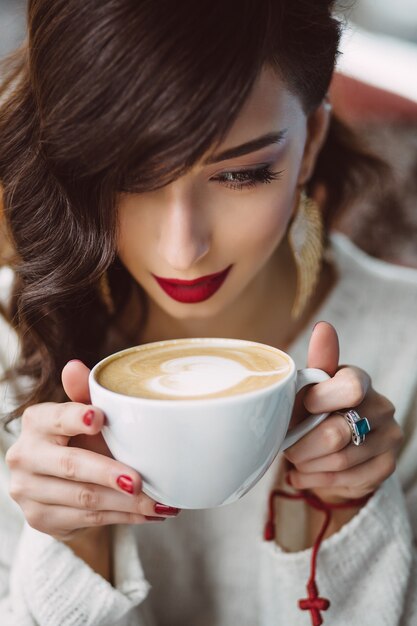 トレンディなカフェでコーヒーを飲む若い女の子