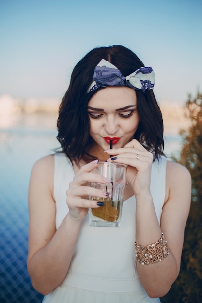 Young girl drinking from a glass by a straw