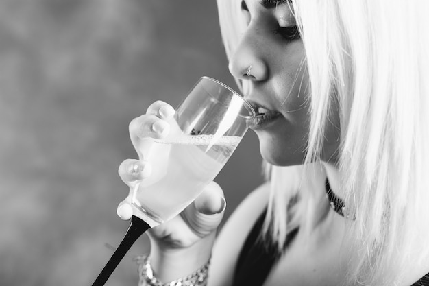 Молодая девушка, выпивая бокал шампанского