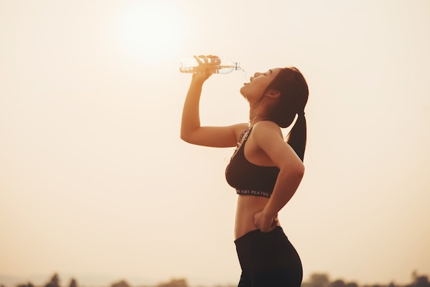 若い女の子がジョギング中に水を飲む