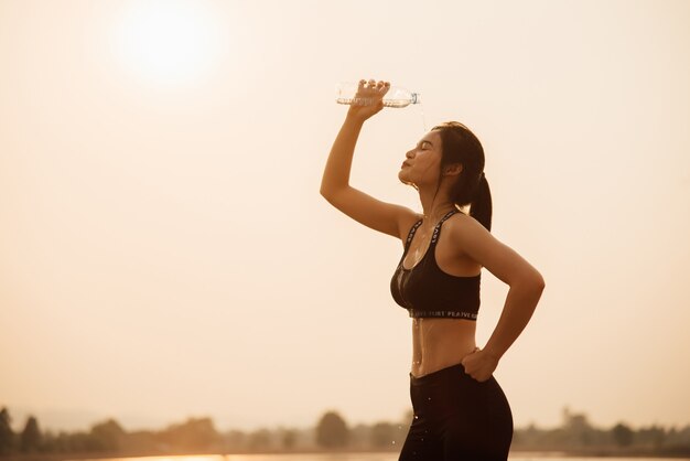 Молодая девушка пьет воду во время пробежки