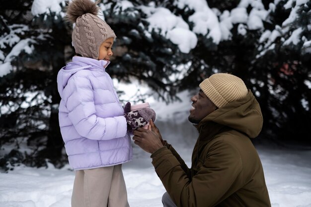 Ragazza che gode di una giornata invernale all'aperto con suo padre