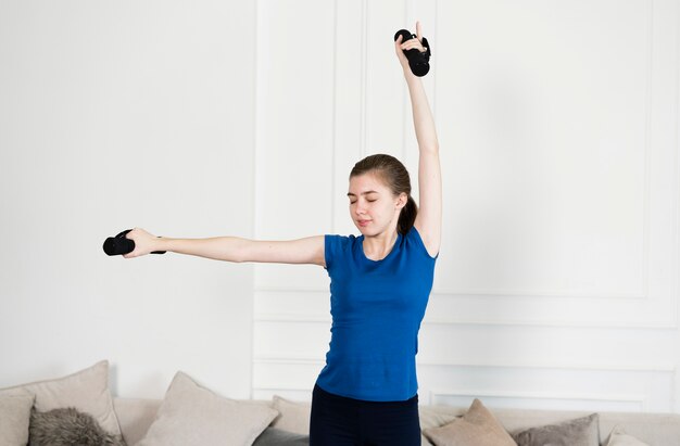 若い女の子が自宅で重みで運動