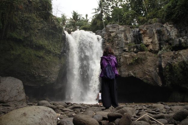 Una giovane ragazza in una cascata gigante vicino al villaggio di ubud a bali