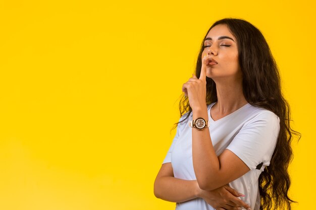 Young girl gives silence sign in a romantic way