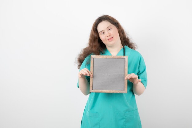 young girl in green uniform holding a frame.