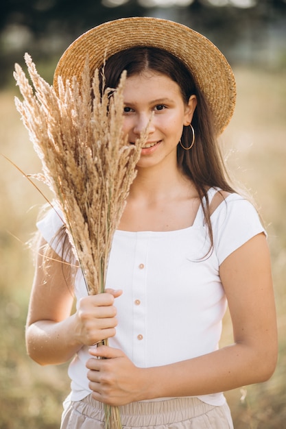 Free photo young girl in a hat in a field of wheat