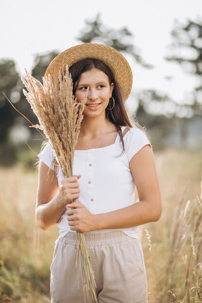 Young girl in a hat in a field of wheat